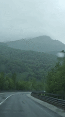 Cars navigate wet mountain road in rainy Kepsha, Russia