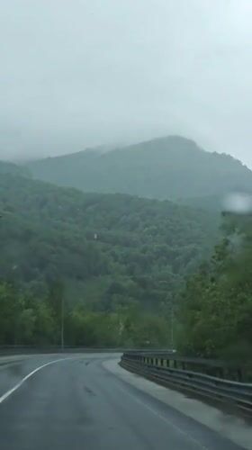 Cars navigate wet mountain road in rainy Kepsha, Russia
