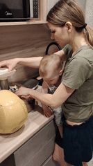 Mother holds baby while cooking in Chaikovsky kitchen