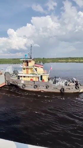 Tugboat tows barge through Russian waterway near Kochino