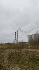 Industrial smokestacks emit white plumes under gray Saint Petersburg sky