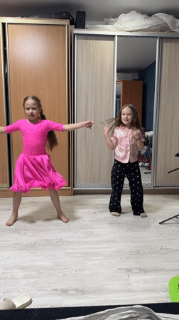 Two girls dance together in bedroom in Rusalevka, Russia