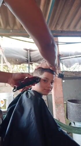 Boy gets outdoor haircut with design in Porlamar, Venezuela