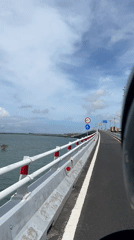 Motorcyclist crosses bridge in Kuta, Indonesia at dawn