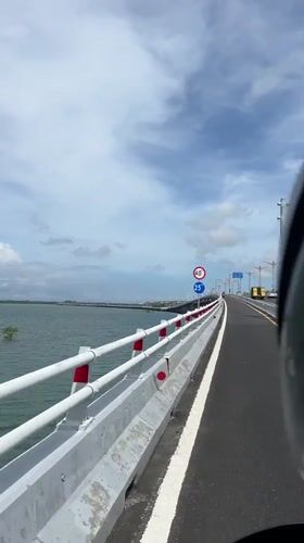 Motorcyclist crosses bridge in Kuta, Indonesia at dawn