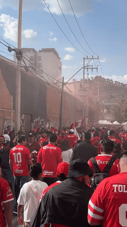 Toluca football fans gather in red jerseys with smoke bombs
