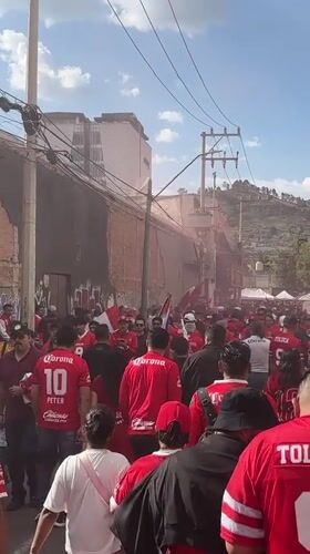 Toluca football fans gather in red jerseys with smoke bombs