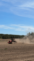Tractor tills dusty field in Belarus countryside