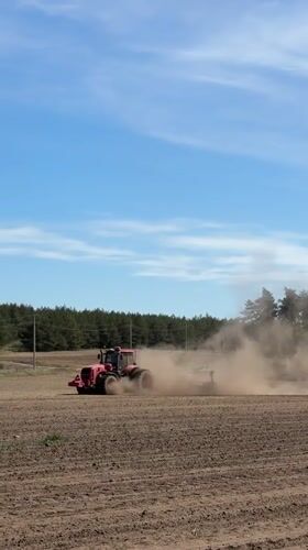 Tractor tills dusty field in Belarus countryside