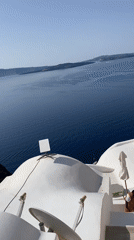 Oia rooftops, Aegean views, and a hat stall on a July morning