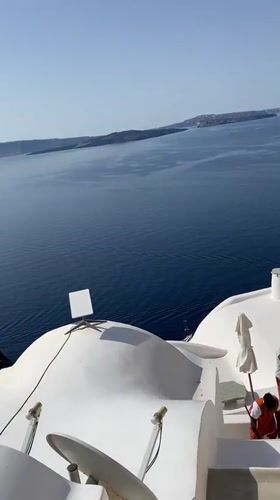 Oia rooftops, Aegean views, and a hat stall on a July morning