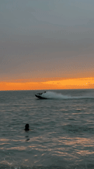 Batumi beach at sunset, jet ski and swimmers in the water
