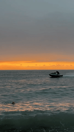 Batumi beach at sunset, jet ski and swimmers in the water
