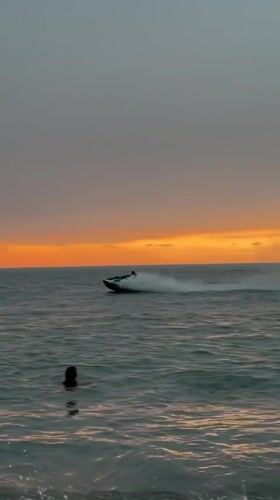 Batumi beach at sunset, jet ski and swimmers in the water