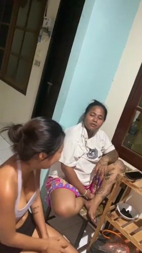 Two women socialize at Kuta guesthouse during evening hours