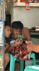 Boys share smartphone in Philippine corner store