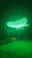 Neon butterfly sculpture illuminates swing set in Thai village