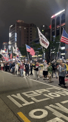 Nighttime flag-bearing procession moves through central Daegu streets