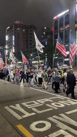 Nighttime flag-bearing procession moves through central Daegu streets