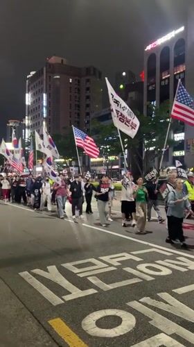 Nighttime flag-bearing procession moves through central Daegu streets