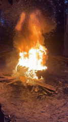 Nighttime campfire burns in Russian clearing with person present