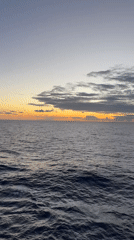 Cargo ship witness captures sunset over calm ocean waters