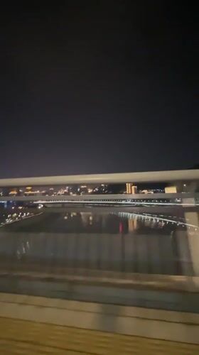 Nighttime cityscape with water reflections filmed from moving vehicle