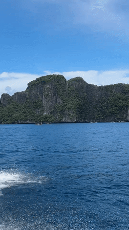 By boat past towering limestone cliffs in southern Thailand