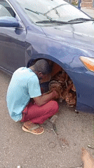 Man repairs car brakes on street in Jos, Nigeria