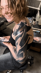 Woman smiles at camera in tattoo studio setting