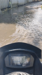Motorcyclist rides through flooded streets in Ko Samui, Thailand