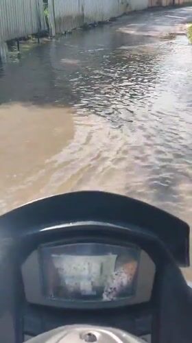 Motorcyclist rides through flooded streets in Ko Samui, Thailand