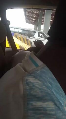 Here's a description of the video:

The video appears to be shot from inside a vehicle, likely a car, as it passes through a toll booth or checkpoint. Through the windshield, a white van with the words "EXPRESS CORPORATION" can be seen. The person filming seems to be in the back seat, and the view is partially obstructed by a person's shoulder and a light-colored garment. Yellow and black hazard markers are briefly visible as the car moves forward.  The environment outside appears to be overcast.