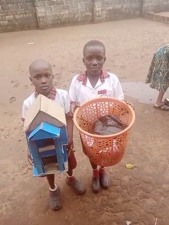 Two young boys wearing school uniforms stand on a dirt ground in front ...