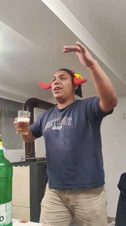 Person in jester hat celebrates with beer in Damianovo