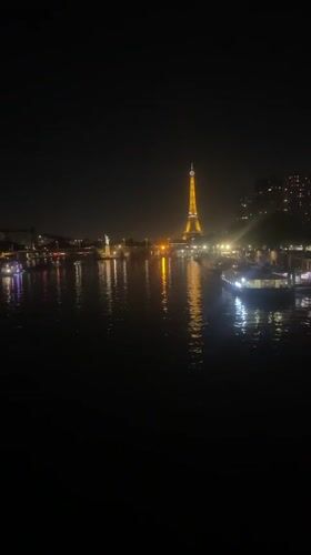 Eiffel Tower glowing gold over the Seine at night