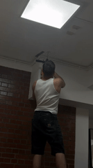 Man drills ceiling wall while standing on makeshift platform