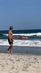 NYPD helicopter circles as beachgoers gather in the surf