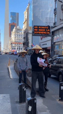 Three people in conical hats hold China sign in Buenos Aires