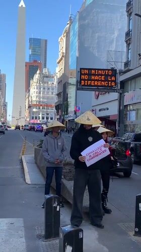 Three people in conical hats hold China sign in Buenos Aires