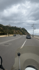 Motorcyclist rides coastal road in Tangier under overcast skies