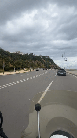 Motorcyclist rides coastal road in Tangier under overcast skies
