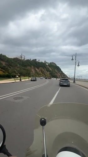 Motorcyclist rides coastal road in Tangier under overcast skies