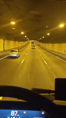 Dashcam drive through tunnel then past a boat-lined waterway