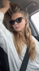 Woman adjusts hair while sitting in car in Kfar Shmaryahu