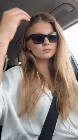 Woman adjusts hair while sitting in car in Kfar Shmaryahu