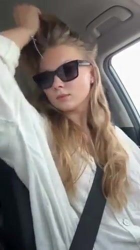 Woman adjusts hair while sitting in car in Kfar Shmaryahu