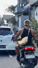Scooter rider travels rural road in Tabanan, Indonesia