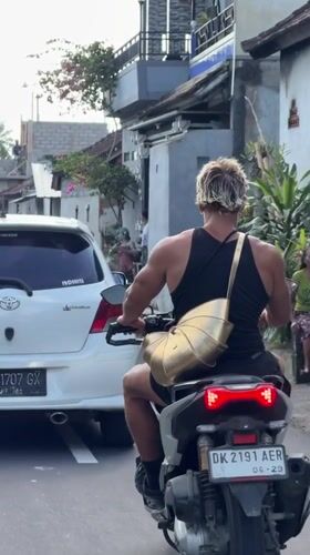 Scooter rider travels rural road in Tabanan, Indonesia