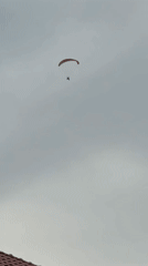 Paramotor pilot flies over Berkovitsa, Bulgaria amid cloudy skies
